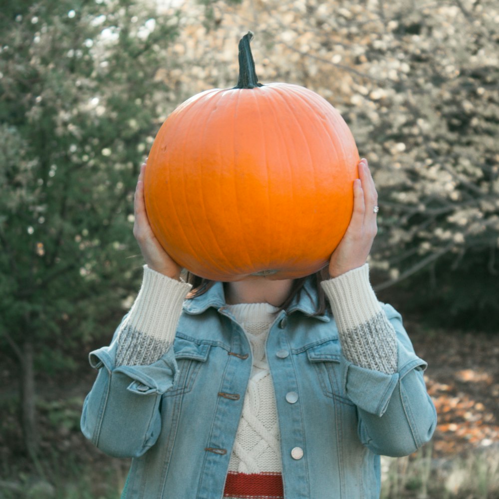 person holding orange pumpkin outdoors