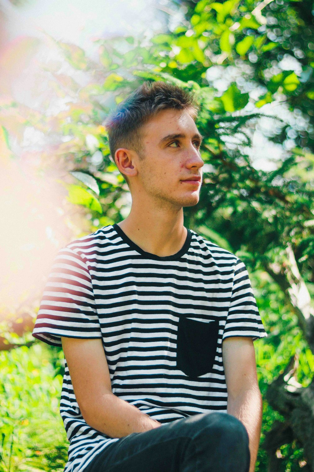 man wearing white and black striped crew-neck shirt looking at side