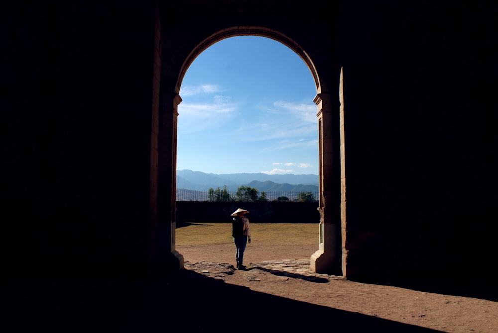 person standing on concrete gate under blue sky