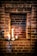 A rustic brick alcove houses three lit candles, creating a warm glow. Green leafy vines and a small decorative stone heart enhance the scene, adding a touch of natural charm.