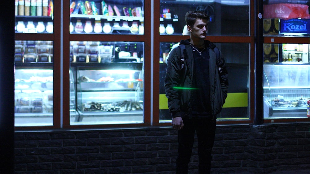 man in jacket standing near glass window