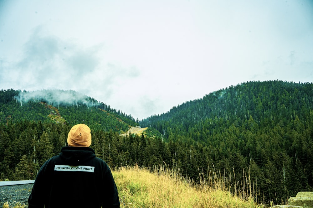man wearing black jacket looking at forest