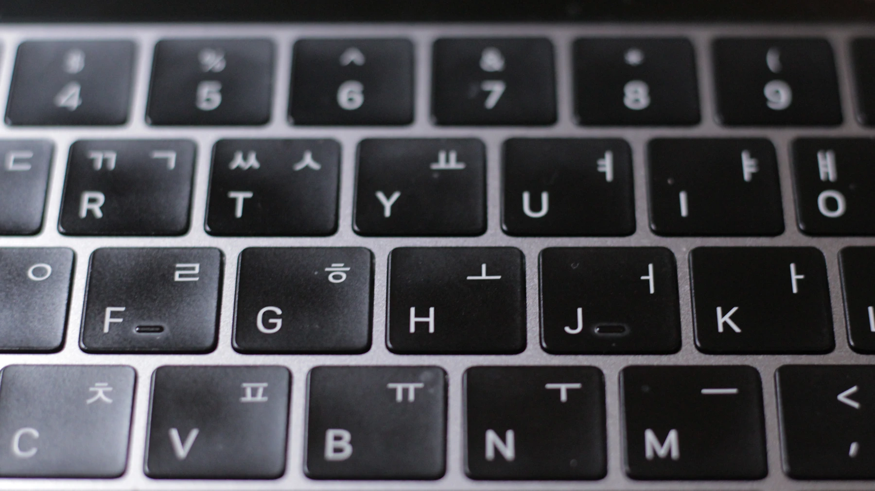 Close-up of a laptop keyboard with a Hangul letter printed beside the Latin letter on each key