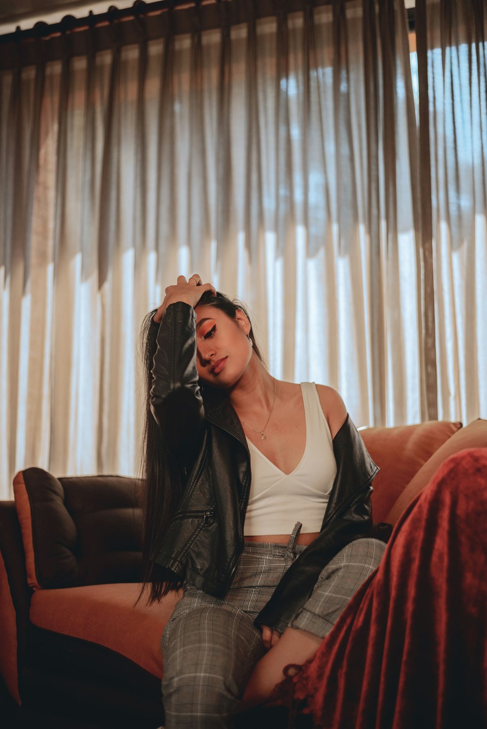 woman sitting on sofa beside window with curtain