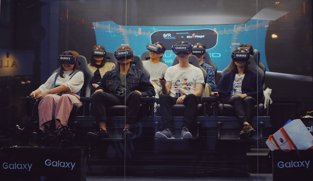 personas sentadas y con cascos de realidad virtual