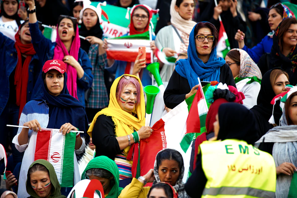 Large crowd of people gathered together, wearing headscarves and holding green and white flags