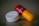 A close-up of two different types of medication. One object is a white round pill with 'PARA 500' written on it. The other is a red and yellow capsule with text inscribed on it.
