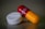 A close-up of two different types of medication. One object is a white round pill with 'PARA 500' written on it. The other is a red and yellow capsule with text inscribed on it.