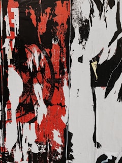A chaotic and abstract composition featuring bold, distressed patterns in black, red, and white, with overlapping layers and vertical streaks. The forms suggest the remnants or peeling layers of street art or graffiti.