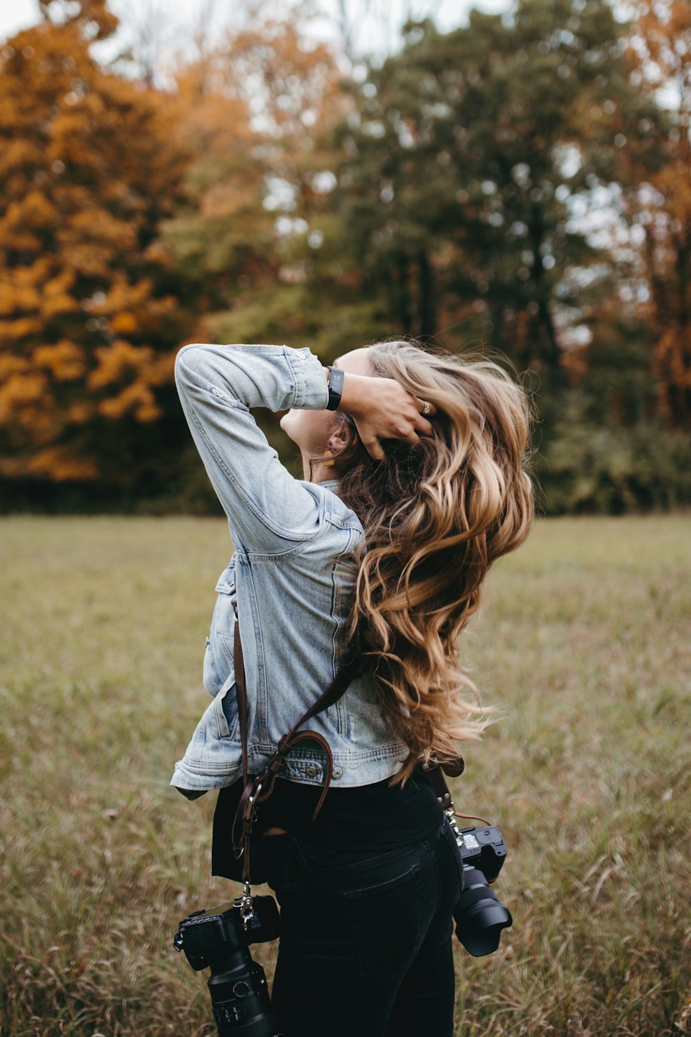 woman standing on grass field with DLSR cameras