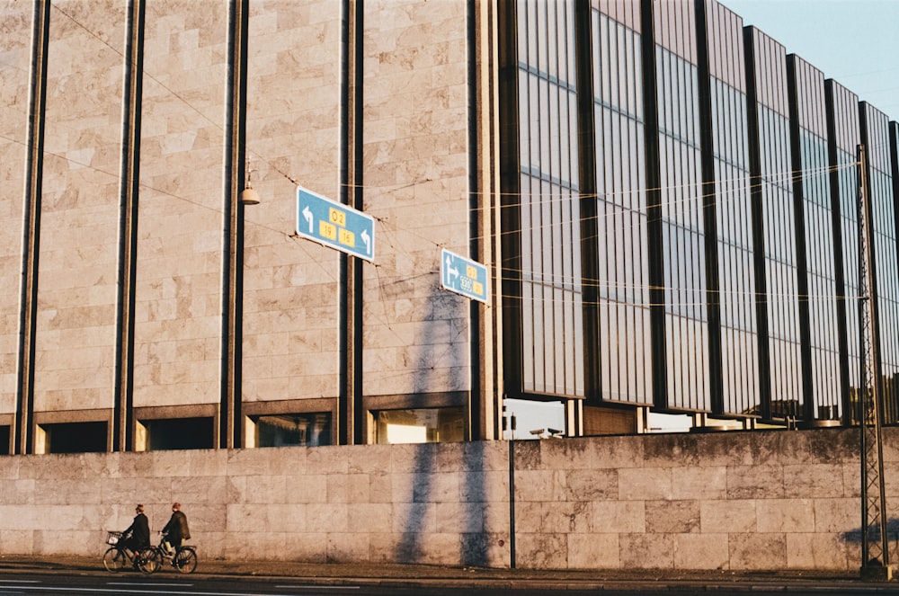 two people riding bikes near wall