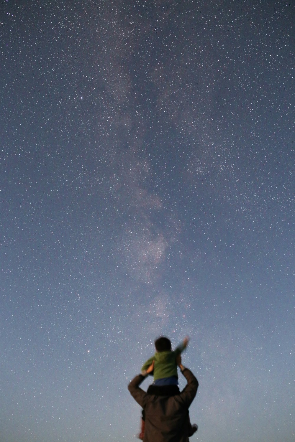 Kleinkind auf dem Ellbogen eines Mannes unter Sternenhimmel