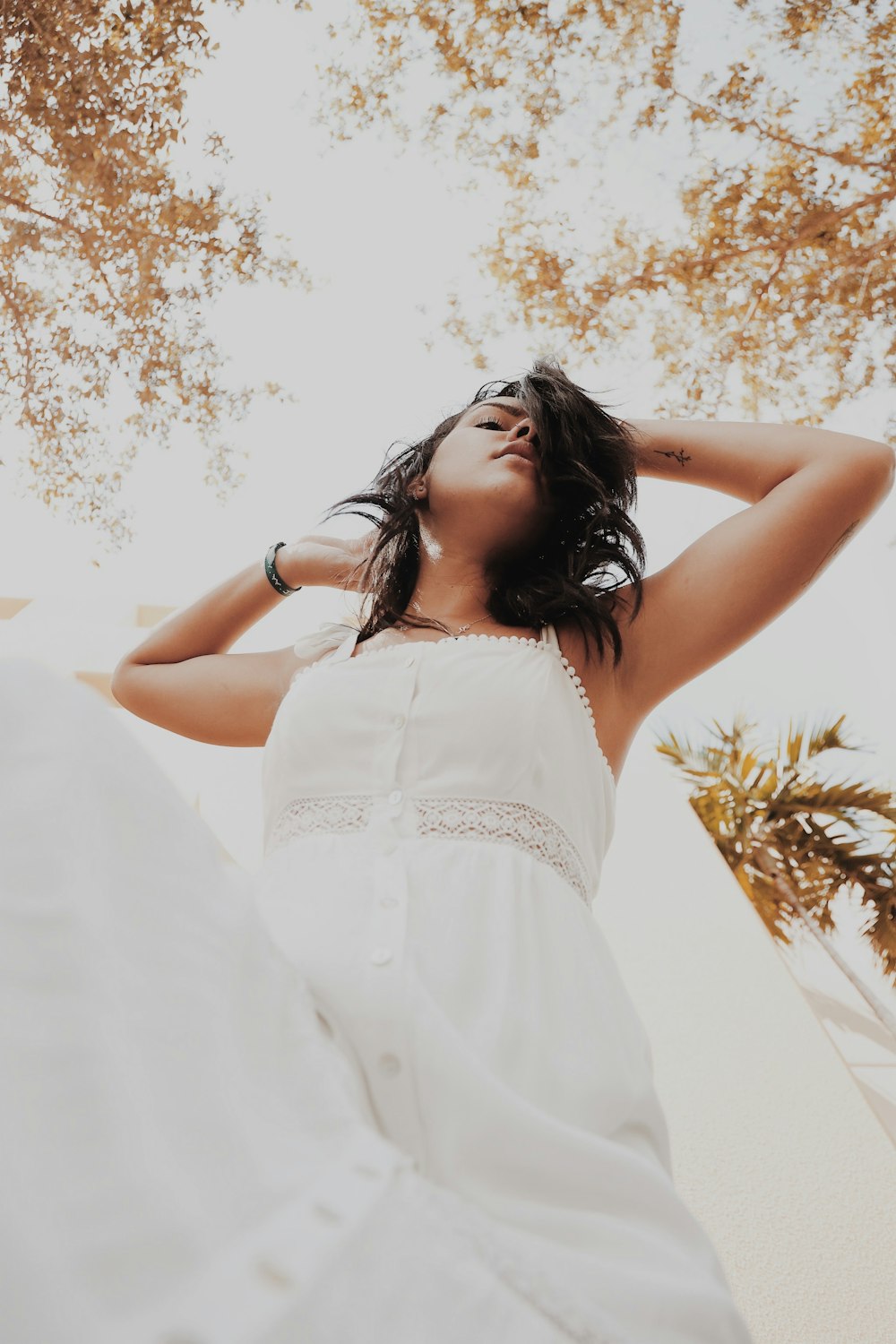 woman wearing white tank dress while holding her head