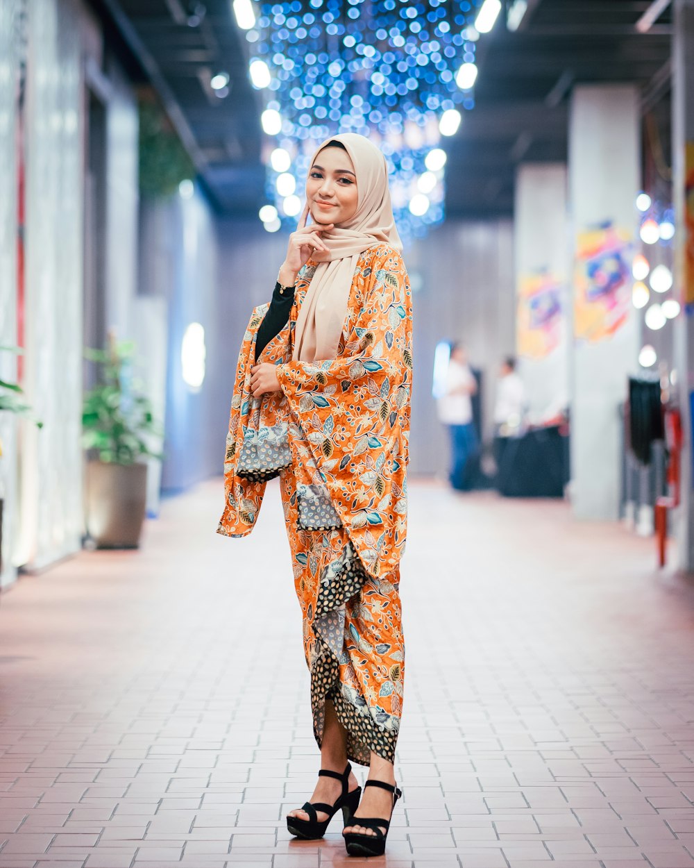 woman wearing orange and multicolored abaya dress standing and smiling