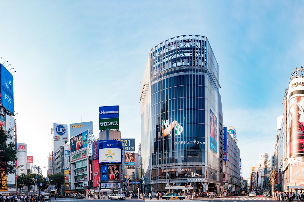 people walking on pathway near buildings and different vehicles on road under blue and white sky during daytime