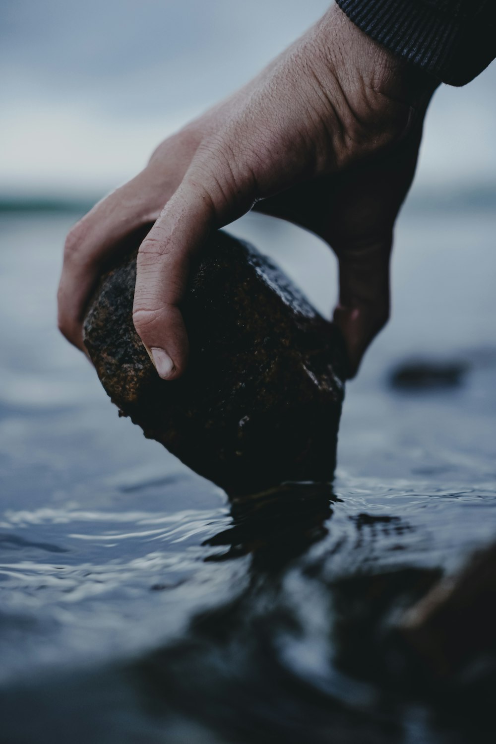 person holding rock over water