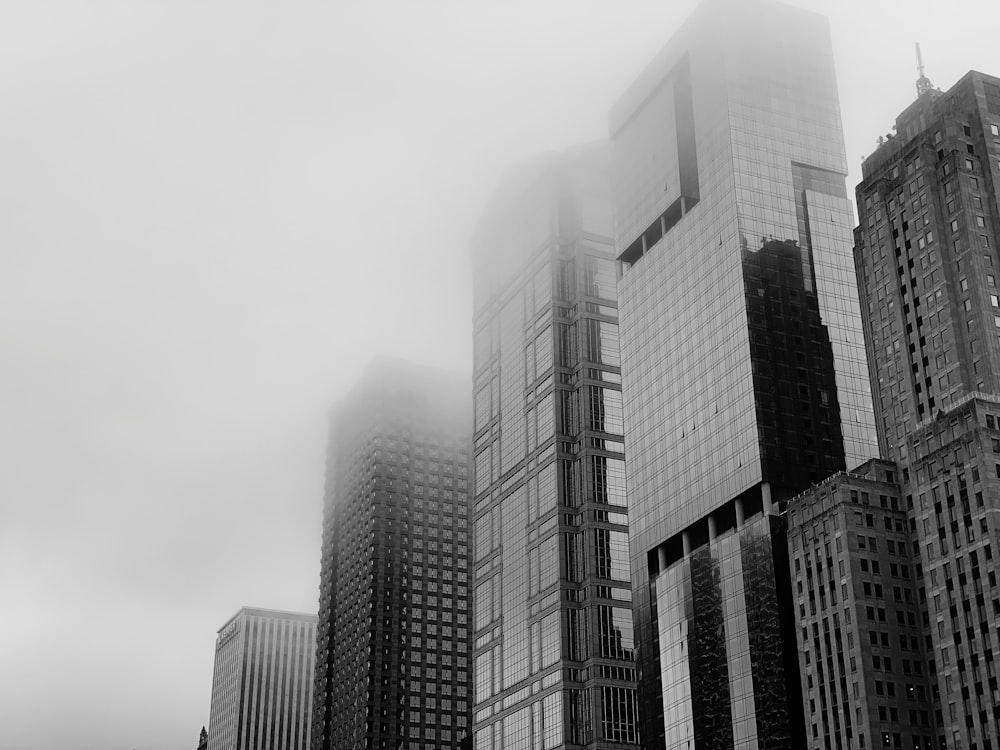 a black and white photo of skyscrapers in the fog