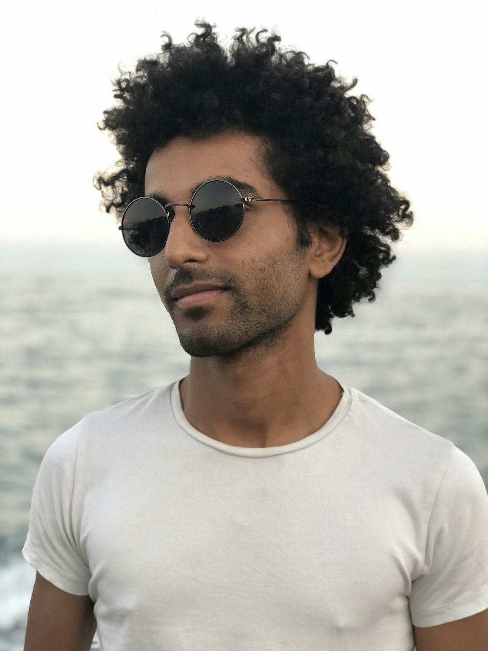 man wearing white crew-neck t-shirt and sunglasses smiling