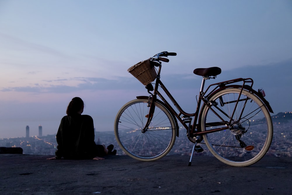 Persona sentada al lado de la bicicleta rígida en blanco y negro