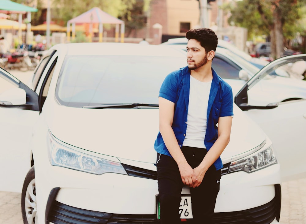 man leaning beside white car