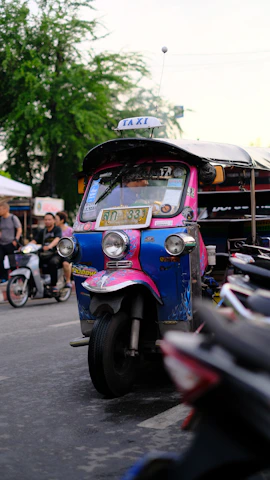 A colorful tuktuk parked near Madrid's historic Plaza Mayor with vibrant city life around