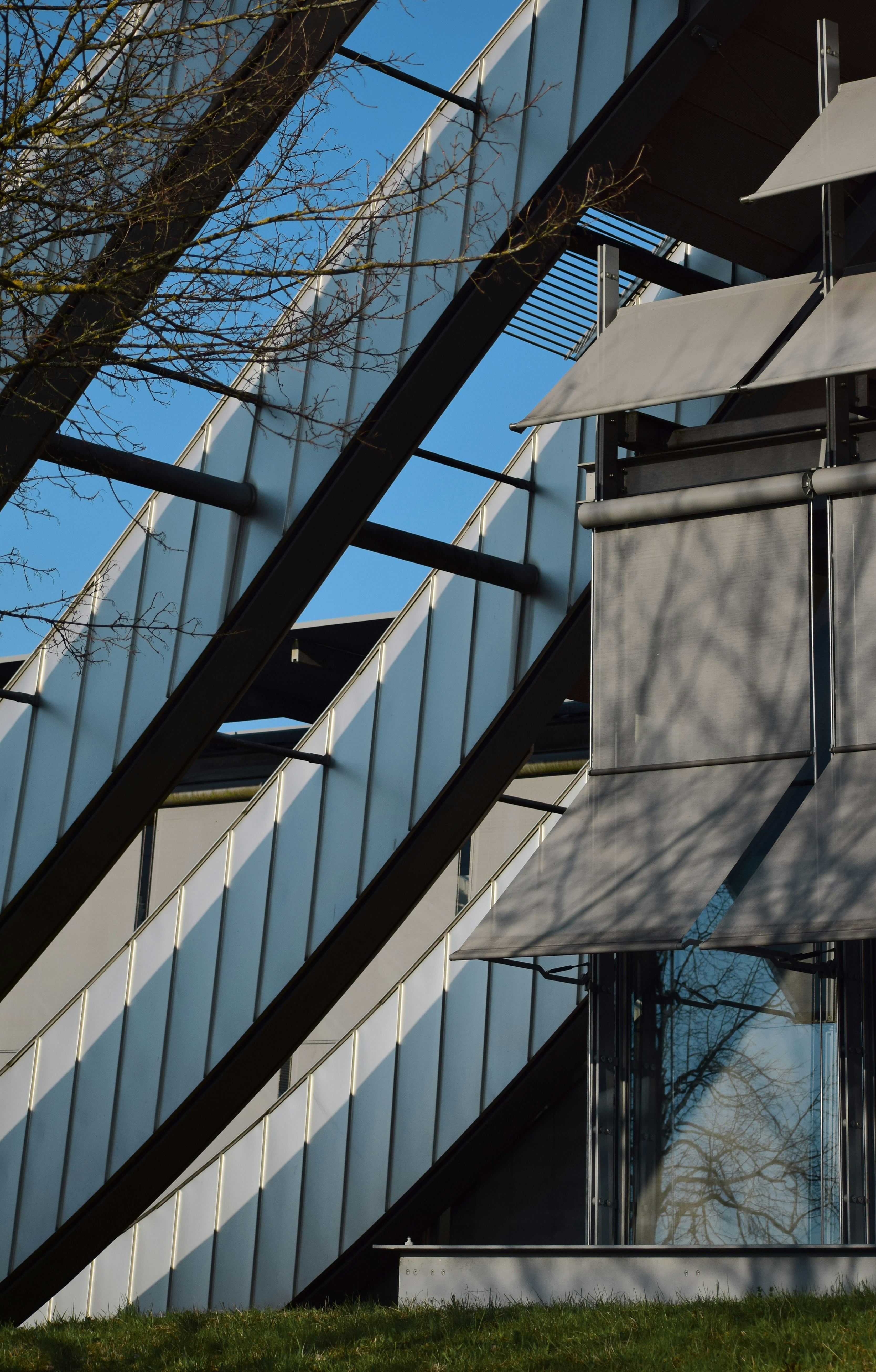 Modern building facade with diagonal metal cladding and grey sunshades.
