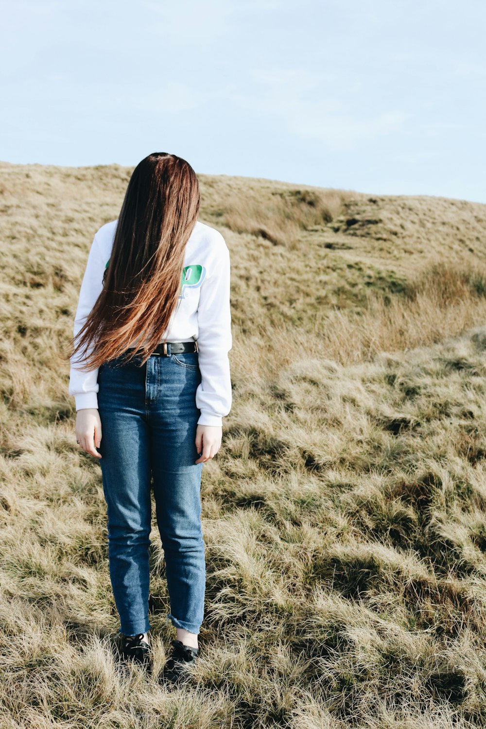 woman wears white jacket and blue denim jeans