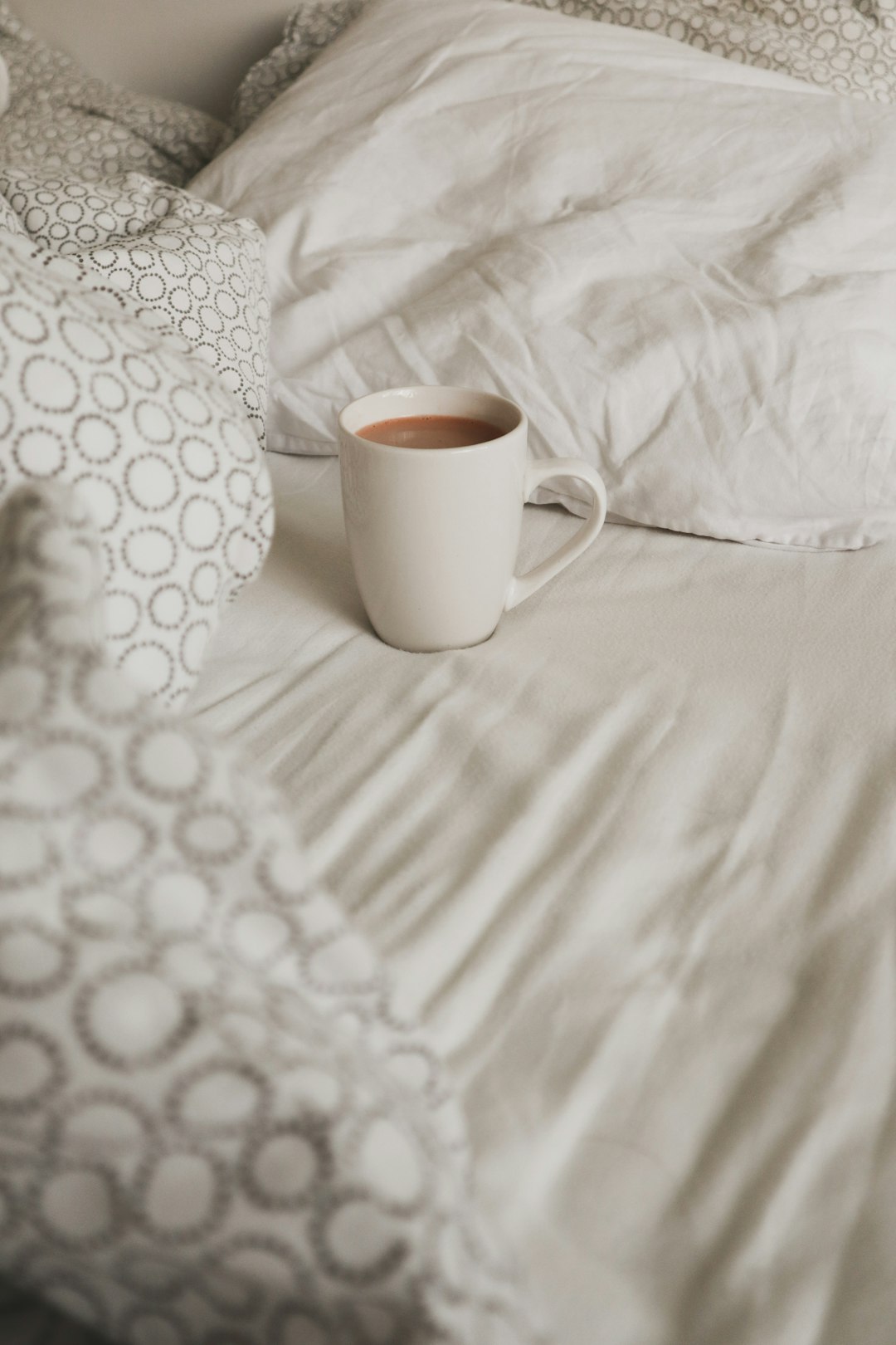 full white ceramic mug on bed