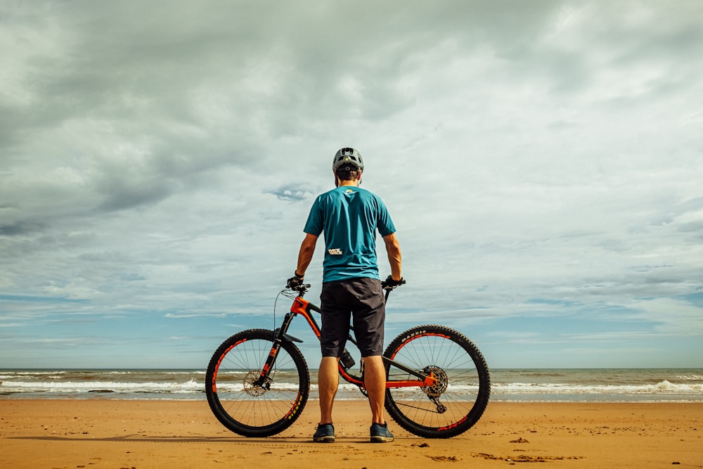 homem em pé ao lado da bicicleta na costa