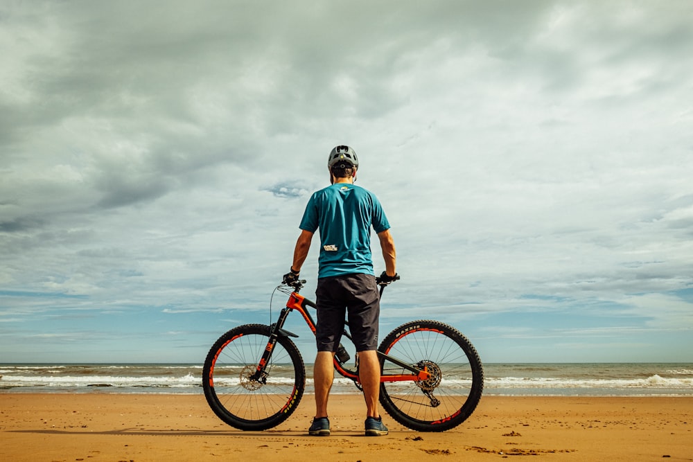 hombre de pie junto a la bicicleta en la orilla del mar