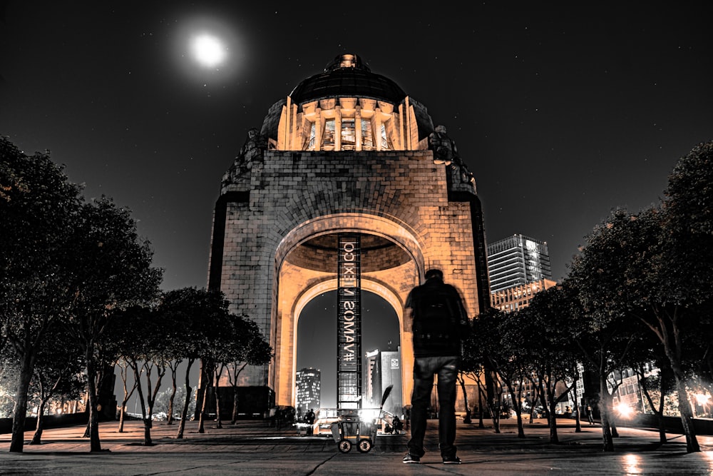 hombre de pie frente a un edificio iluminado por la noche