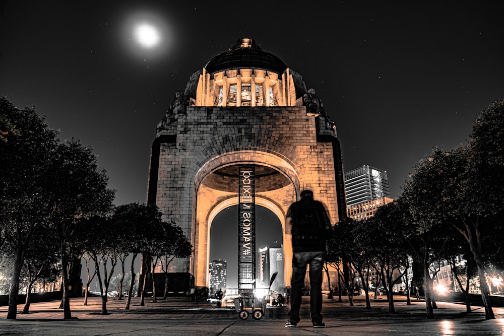 man standing front of lighted building at night