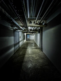 empty underground hallway with pipes on ceiling