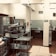A professional kitchen setting with stainless steel shelves and countertops, featuring an array of kitchen supplies and equipment. The room has tiled flooring and walls, with various silver and gray tones dominating the decor.