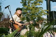 A smiling student playing guitar on a sunny day outdoors.