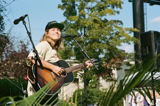 A smiling student playing guitar on a sunny day outdoors.