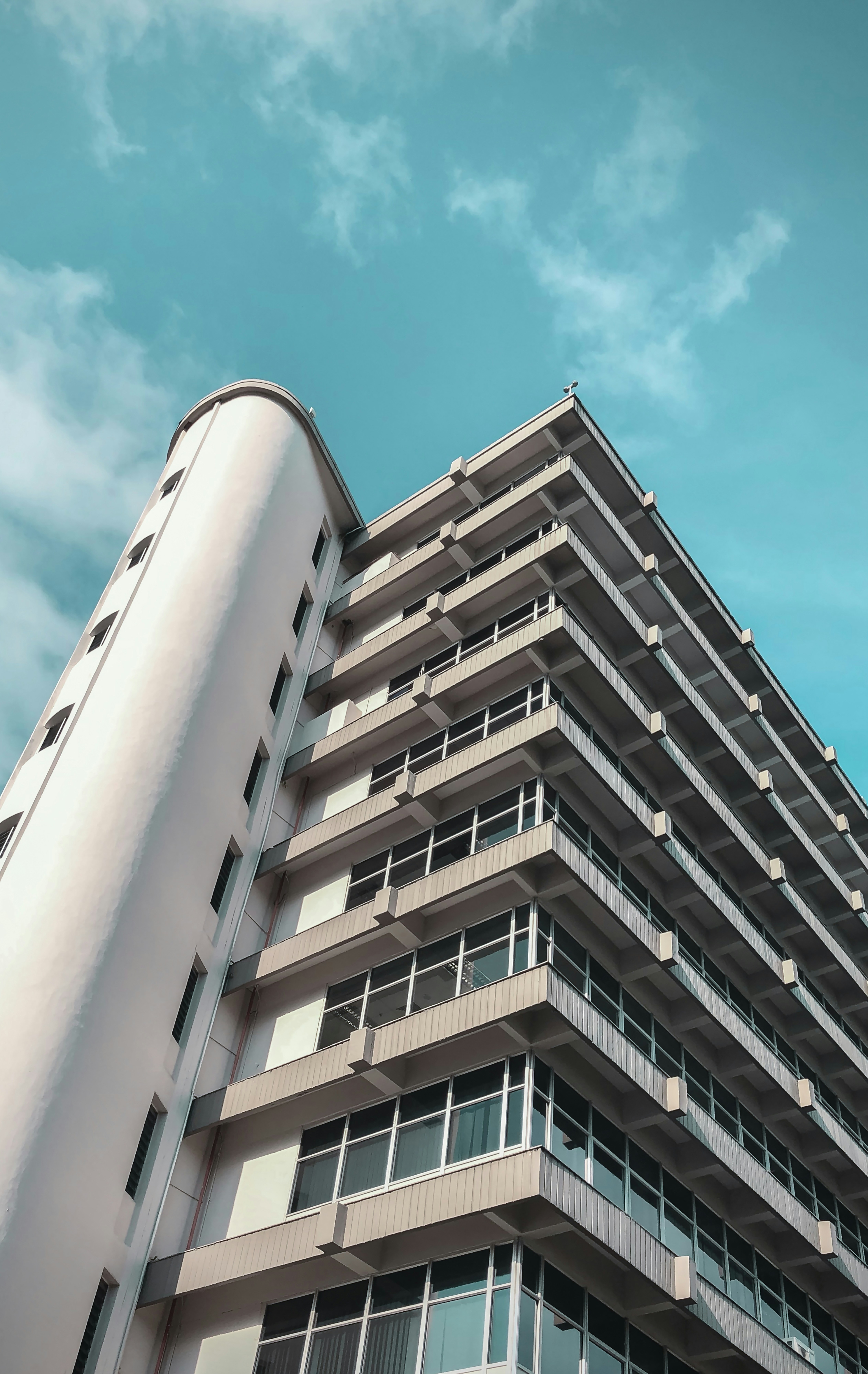 low-angle photography of white high-rise building under blue and white sky during daytime