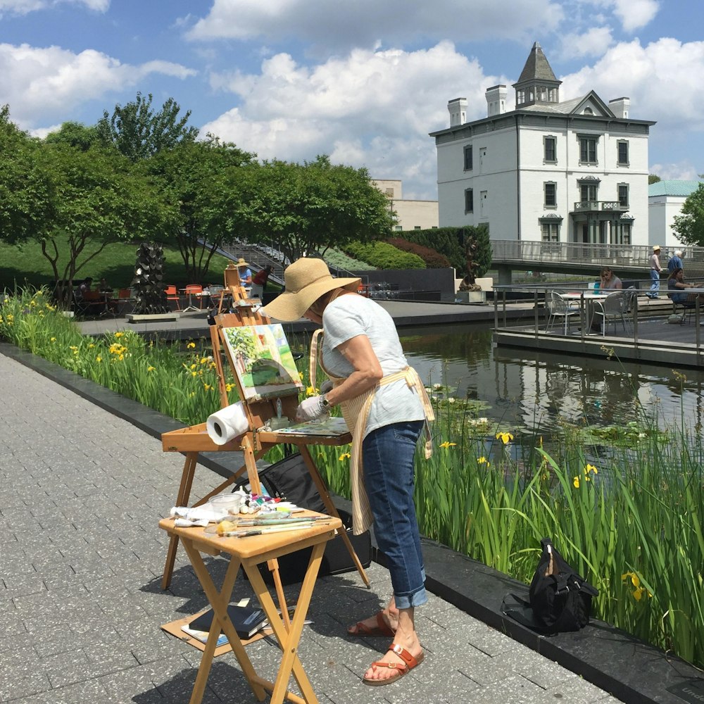 woman painting by a pond