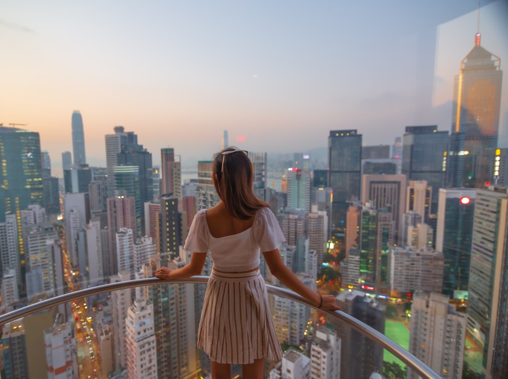 woman wearing dress leaning on railing overlooking at buildings