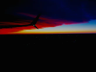 Sunset silhouette of a jet ascending against a deep navy sky.