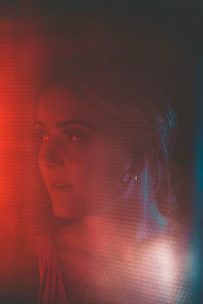 A sensual woman smiling softly in a dimly lit room, evoking mystery and allure.