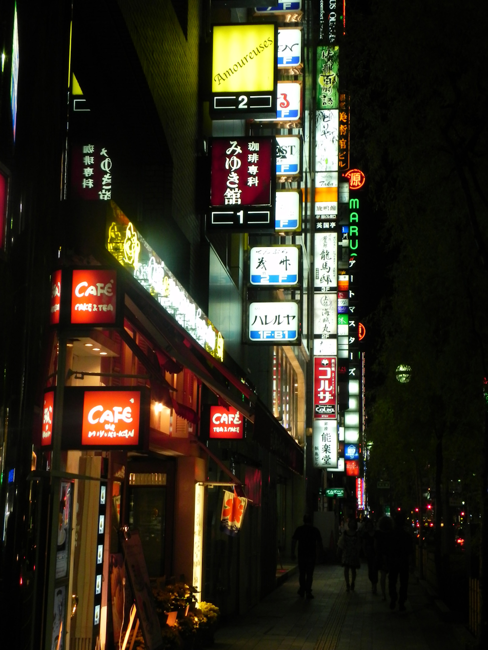 a city street at night with neon signs on the buildings