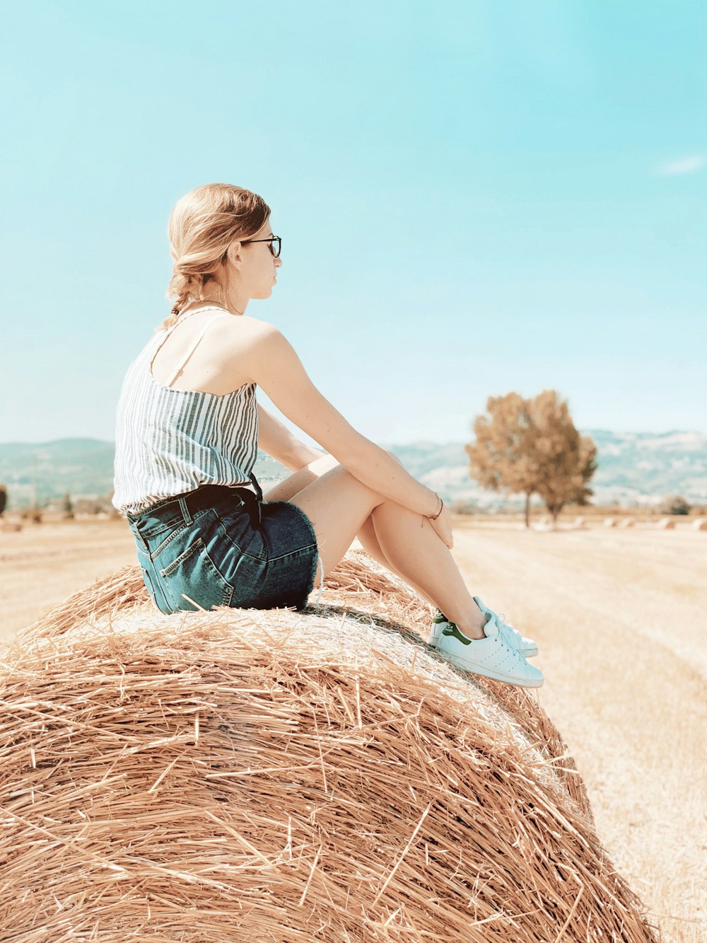 woman in white top sitting on hay