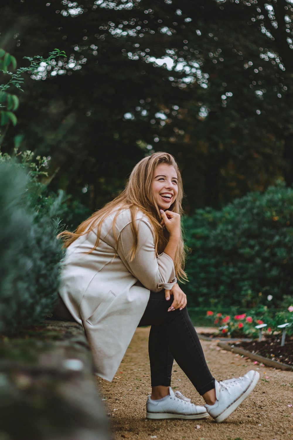 smiling woman brown coat sitting beside plant