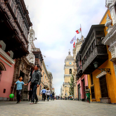 A vibrant street scene in Malabo showing colorful colonial buildings and local artists performing traditional dance.