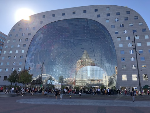 A bustling commercial building with large windows and people entering and exiting.