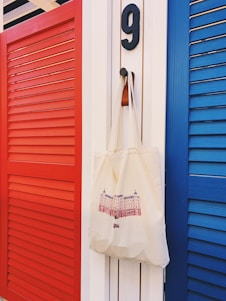 white tote bag hanging beside red door
