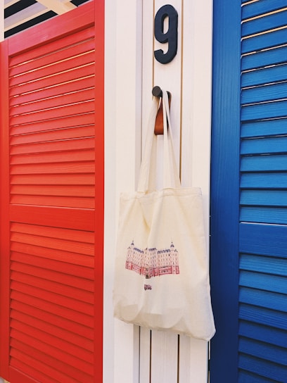 white tote bag hanging beside red door