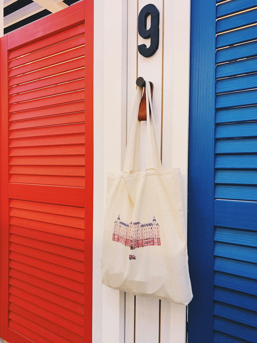 white tote bag hanging beside red door