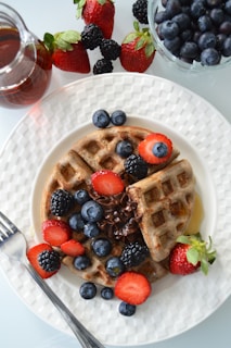 A plate of golden waffles topped with fresh berries and a drizzle of syrup